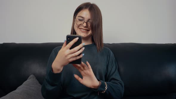 Portrait of a Redhaired Young Woman Talking on a Video Call on the Phone at Home alt
