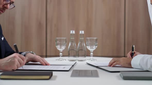 Businessman Sign Contract Documents with a Arab Partner While Sitting at the Table a Handshake alt