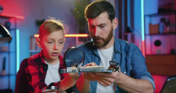 Father Holding Electronic Scheme in His Hand while Curious Teen Son alt