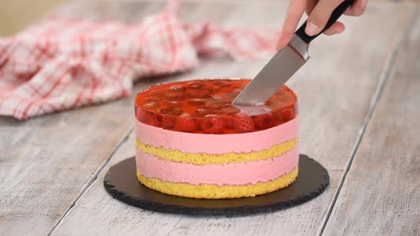 Female Hands Cutting Sweet Cake with Raspberry Mousse and Layer of Jelly alt
