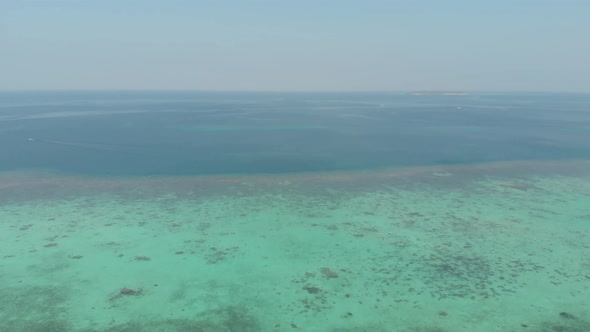 Aerial: Flying over tropical island and coral reef in Indonesia alt