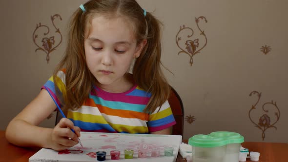A Cute Little Girl is Happy to Paint While Sitting at the Table