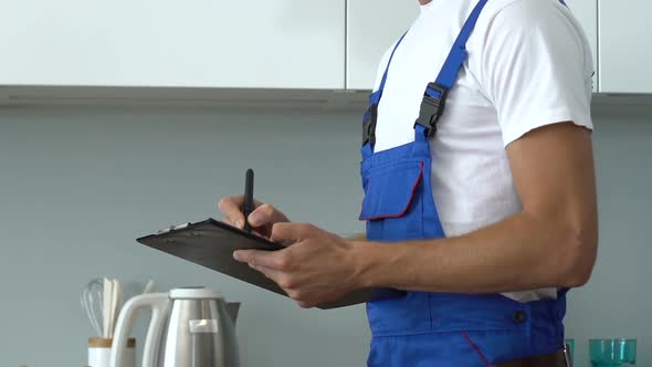 Handsome repairman workwear writing list of job done alt
