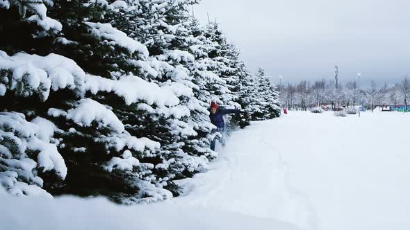 Joyous Man Runs Next To the Snowy Trees and Knocks Down the Snow From the Branches, Slow Motion alt