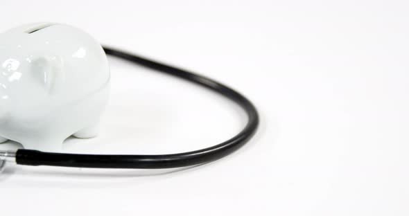 Stethoscope and piggy bank on white background alt