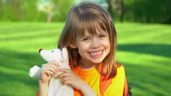 Child Girl with School Backpack Smiles and Laughs on Lawn