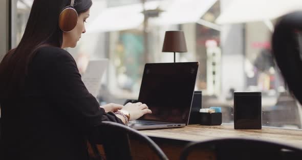 Back View of Caucasian Woman Working on a New Project in a Coffee Shop alt