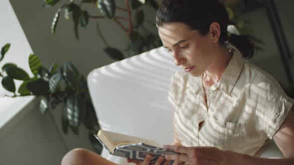 Woman Reading Book and Posing for Camera at Home alt