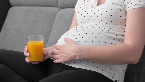 Pregnant Woman on Sofa with Glass of Orange Juice