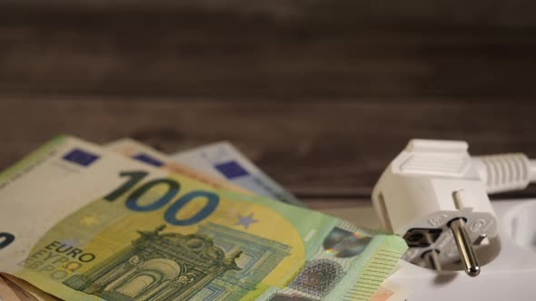 Pile of Cash on a Socket Showing the High Electricity Price Concept alt