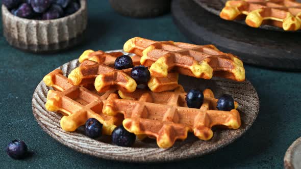 Pouring honey on belgian waffles served with blueberries. Sweet breakfast