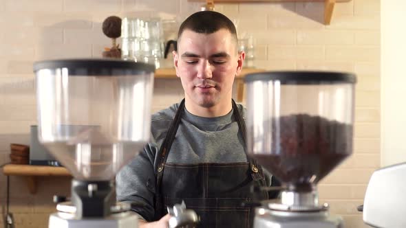 Barista Makes Espresso in Cafe, He Throws a Portafilter in His Hand. alt