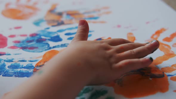 Little Girl with Paints on Her Hands Draws on White Paper alt