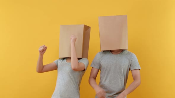 Anonymous couple cover head with paper bags doing funny dance o