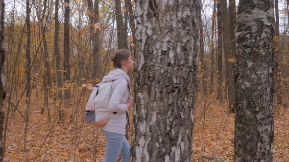 Young Woman with Backpack Walking in Autumn Park  Steadicam Shot
