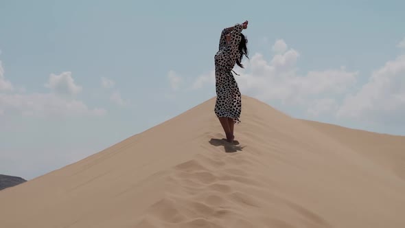 Girl in a Bright Dress Walking Barefoot Along the Dunes in the Desert alt