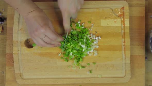 Woman Chopping Purple Onion, Lettuce, Parsley at Wooden Kitchen Table