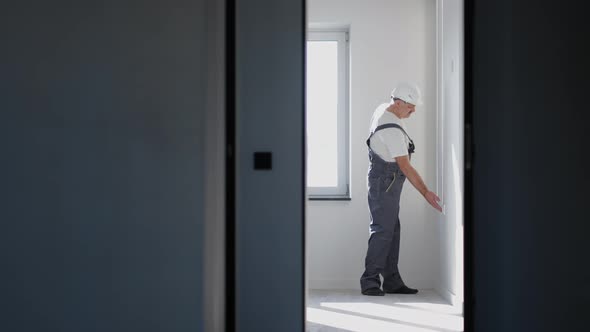 An Electrician in a Helmet Installs and Checks LED Strips for Illumination in the Apartment alt