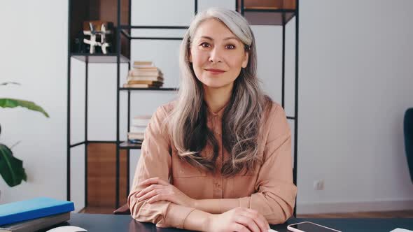 Smiling Mature Businesswoman Sit at Desk in Office Talk with Client Customer Have Conversation on alt