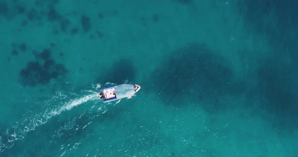 Aerial view of the fishing boat in transparent blue water at sunny day in summer