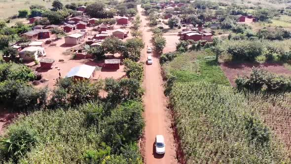 Tourists Driving Cars on Road of Rural African Village, Drone View alt