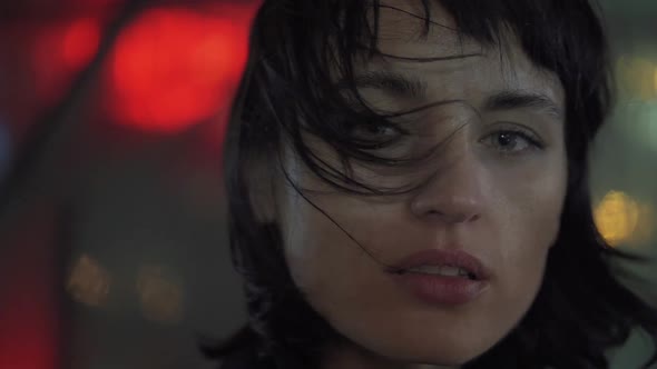 Melancholic Emotive Caucasian Female Standing Looking at You In The City At Night While It Rains alt