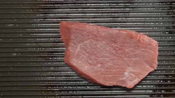 Fresh beef steak falls on a grill 