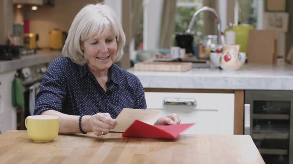 Senior Adult Woman opening Valentine's Day Card at kitchen table