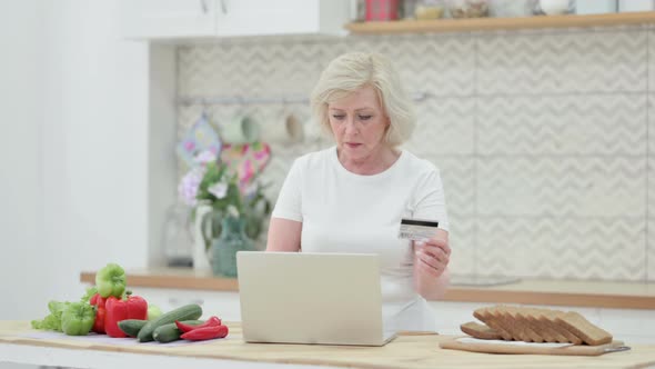 Attractive Senior Old Woman Making Online Payment on Laptop in Kitchen alt