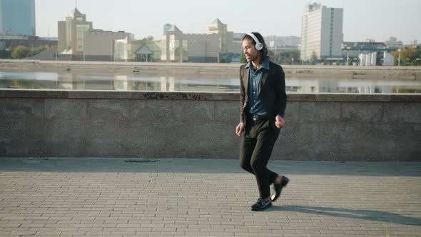 Dance Loop of Joyful Mixed Race Man Wearing Headphones Having Fun Outside in River Embankment alt