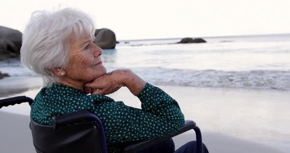 Woman sitting on wheelchair at beach 