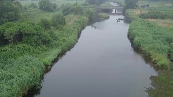 Panning from left to right above the river Otter in Devon England. The river is surrounded by fields alt