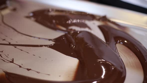 Confectioner is Working with Melted Chocolate Using Putty Knife alt