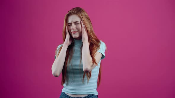 The Stressed Redhaired Young Woman Puts Her Hands to Her Head As a Sign of Fatigue and Looks alt
