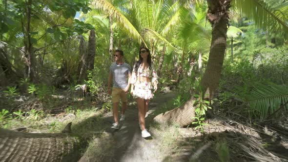 A man and woman couple walking on a path in the tropical islands in French Polynesia alt