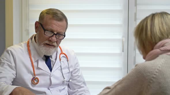 An Elderly Experienced Male Doctor Assesses the Symptoms of a Patient's Illness alt