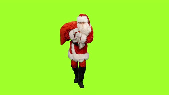 Santa Walking with Christmas Gifts in Sack on Green Background