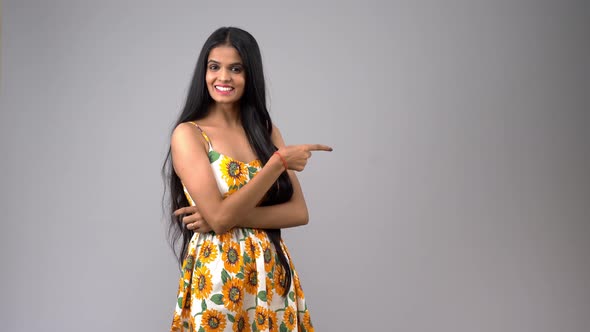 A beautiful and attractive Indian girl pointing to the right for product placement for image, etc. alt