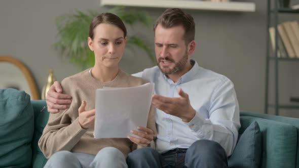 Couple Having Failure While Reading Documents on Sofa alt