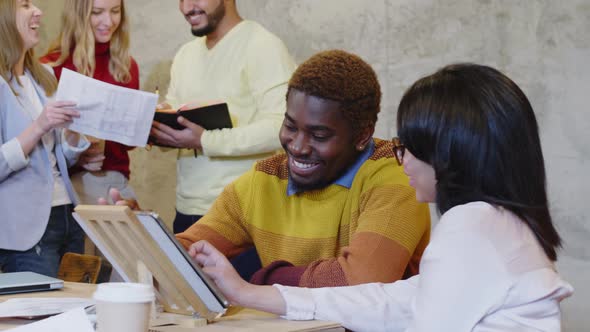 Diverse Coworkers Discussing Project on Tablet in Office