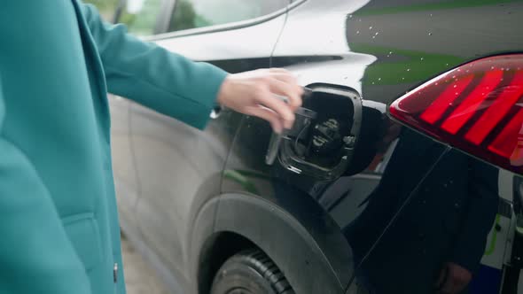 Business woman opens the tank to refuel the car with gasoline or diesel fuel at the gas station.