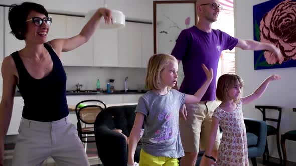 Family with three female children indoor at home playing videogame together dancing alt