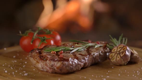 Grilled Beef Steak on Wooden Board on Fire Background 