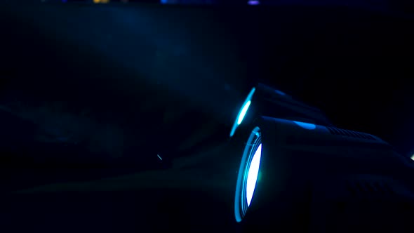 Close up of professional spotlights switching colours fast. Smoke makes light beams visible. alt