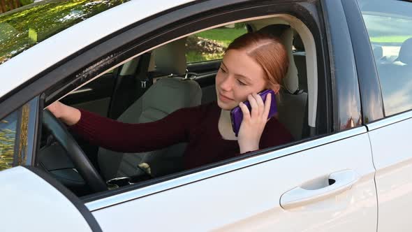 An otherwise friendly teenager talks on her cellphone in a car.  She gives a passerby a quick nasty alt