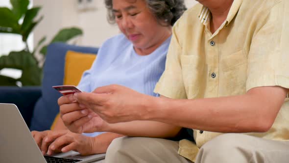 Asian senior couple using laptop searching online shopping.