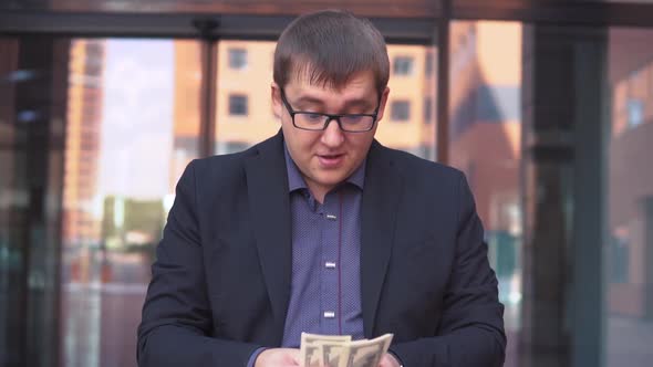 A Businessman Counts Money Standing Near the Business Center alt