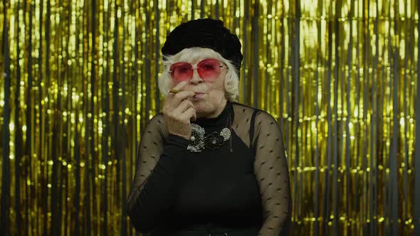 Elderly Style Mature Woman in Fashion Clothes in Sunglasses Posing, Smoke Electronic Cigarette alt