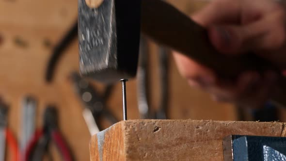Caucasian hand hammering a nail into a piece of wood in diy home workshop alt