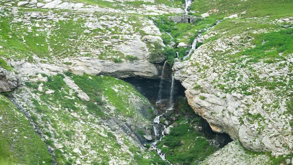 Looking out over green hills with waterfalls in the distance in Barcelonnette, France. alt